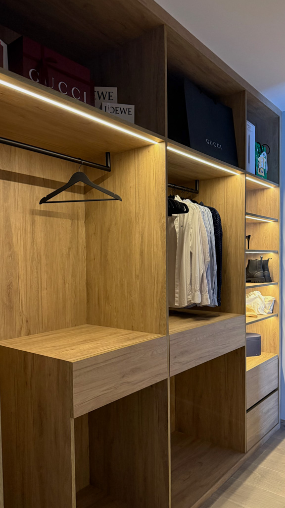 Vestidor a medida: distinción y comodidad 1 Vestidor lineal abierto a medida hecho en roble con cajoneras y guías ocultas, barras de colgar a medida con forma de U en color negro, baldas para almacenar zapatos e iluminación integrada